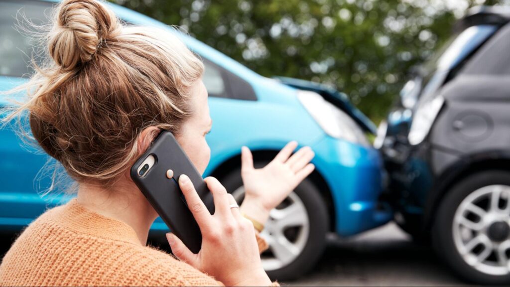 Woman making a phone call after a rear-end collision between two cars.