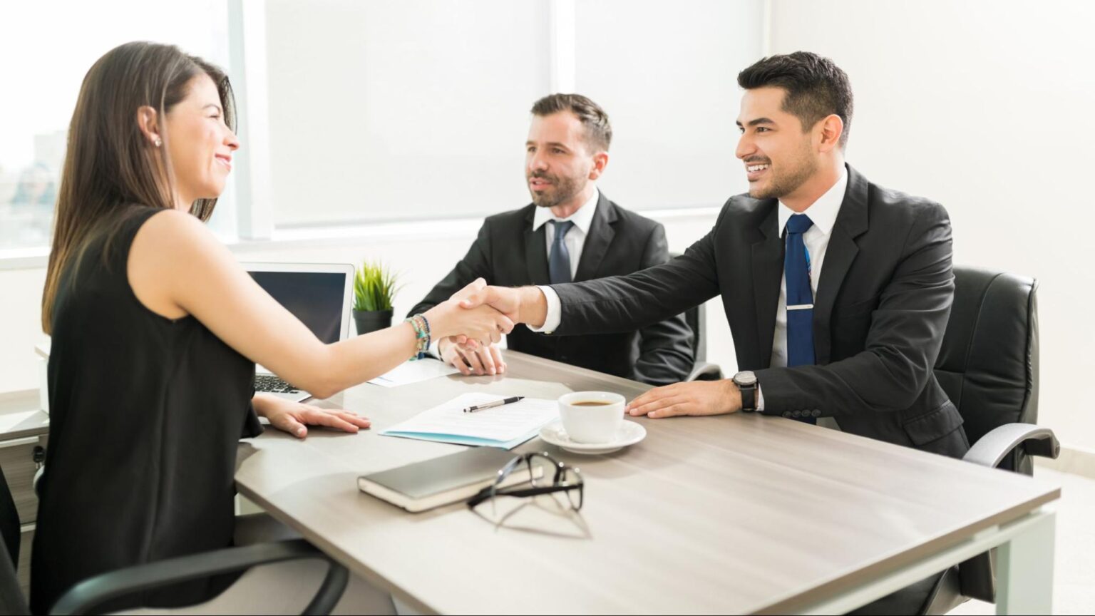Businesswoman shaking hands with two attorneys during a meeting