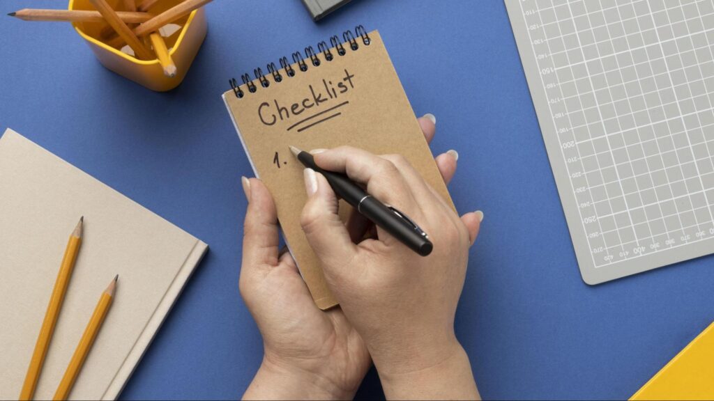 Close-up of a person writing a checklist in a notebook on a desk