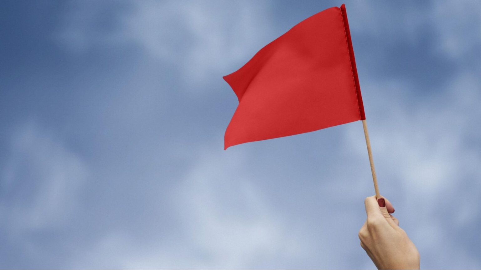 A hand holding a red flag in the air, symbolizing the warning signs of fake lawyers and legal scams in Florida.