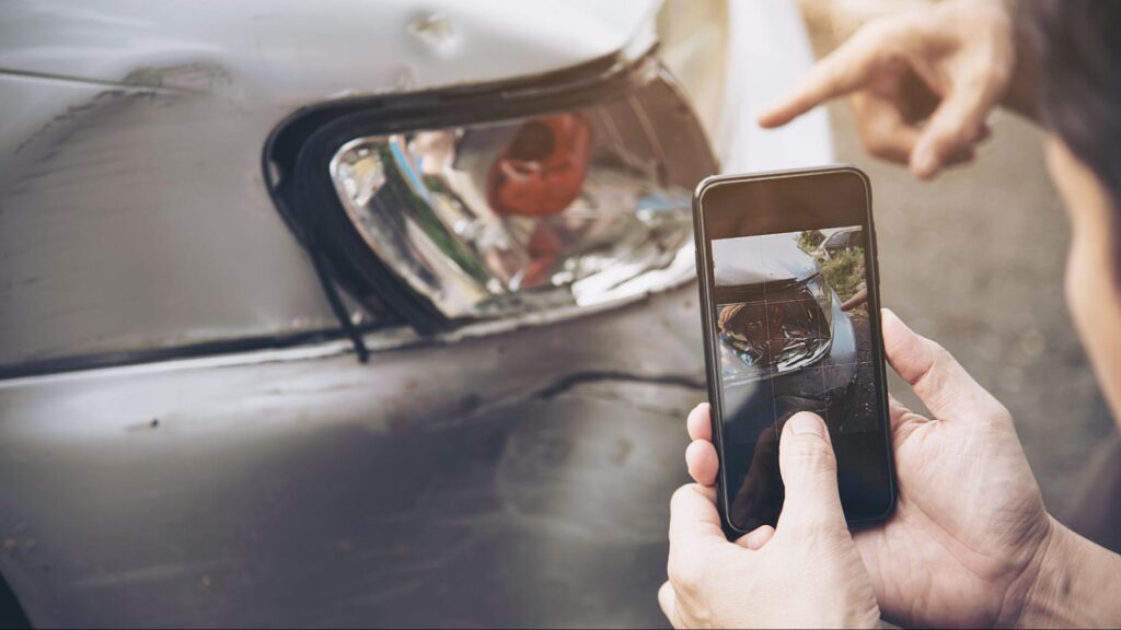 Driver taking photos of car damage after a car accident during the holiday in Florida to document evidence for insurance.