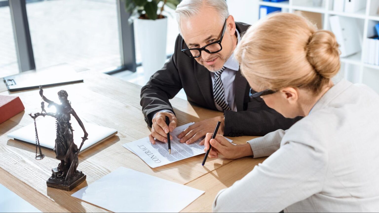 Two experienced Florida personal injury lawyers discuss a client's legal case and insurance policy terms at a desk, reviewing the difference between a bodily injury and economic damages.